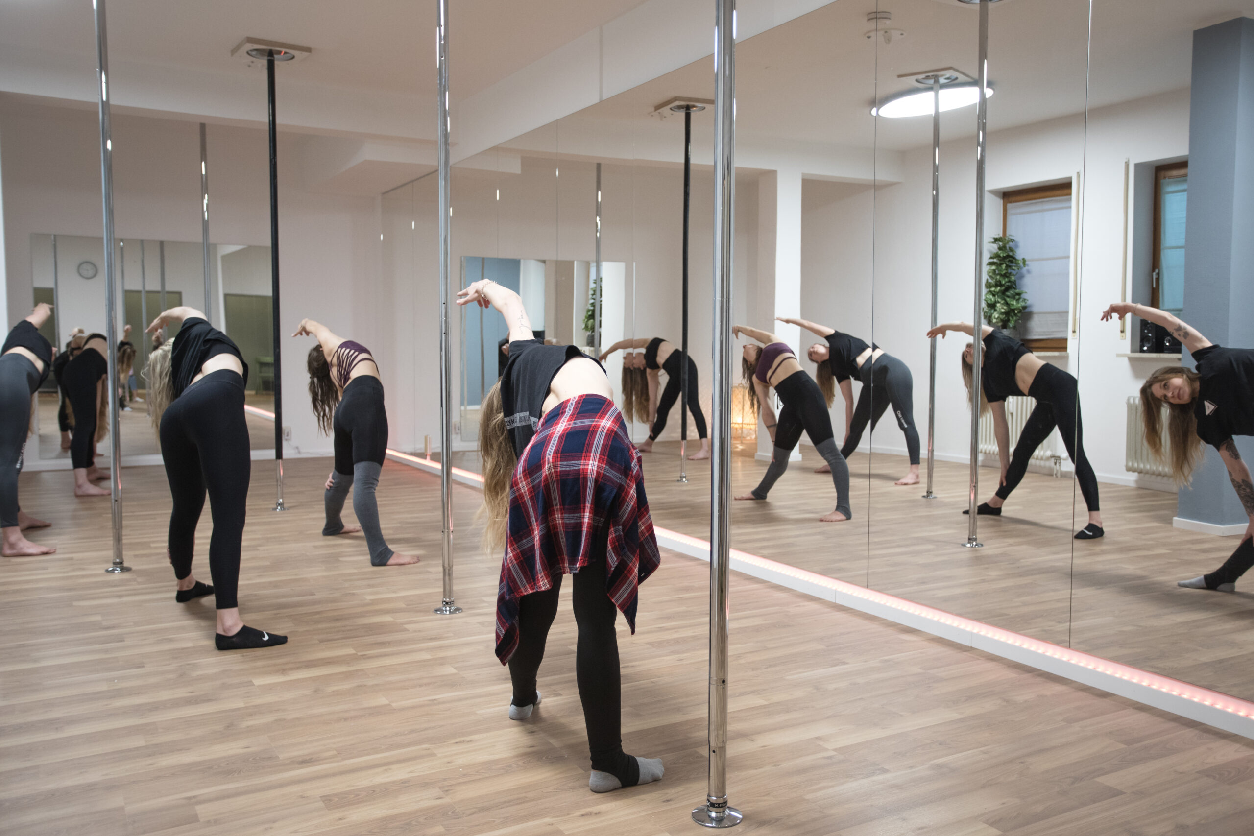 Sportlerinnen im Poledance Studio beim Trainieren vor einer Spiegelwand